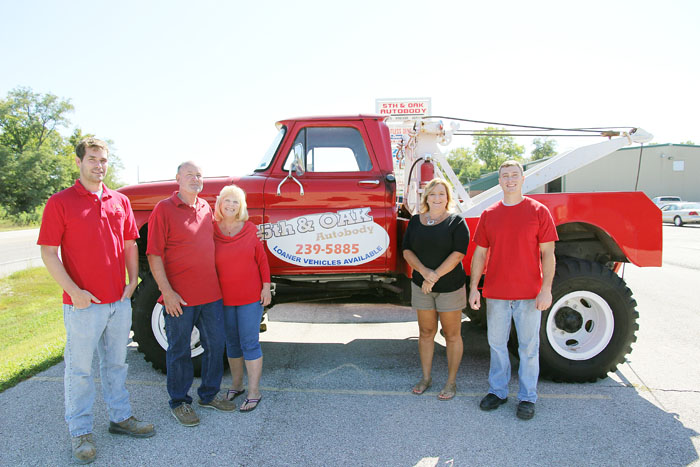 The family behind 5th & Oak Autobody standing in front of their vintage red tow truck