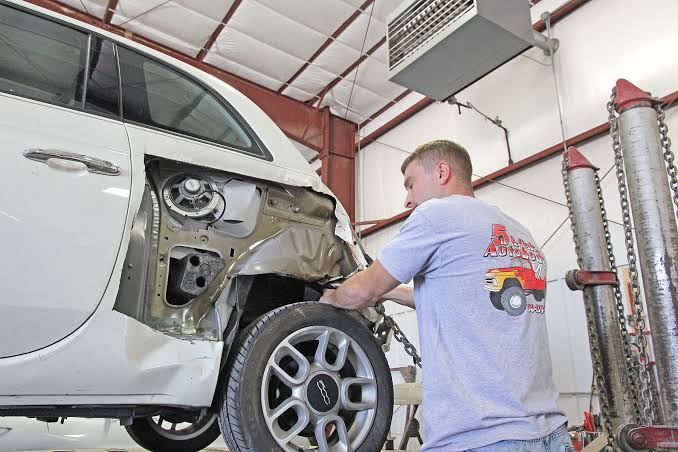 Technician repairing the rear quarter panel of a white car at 5th & Oak Autobody