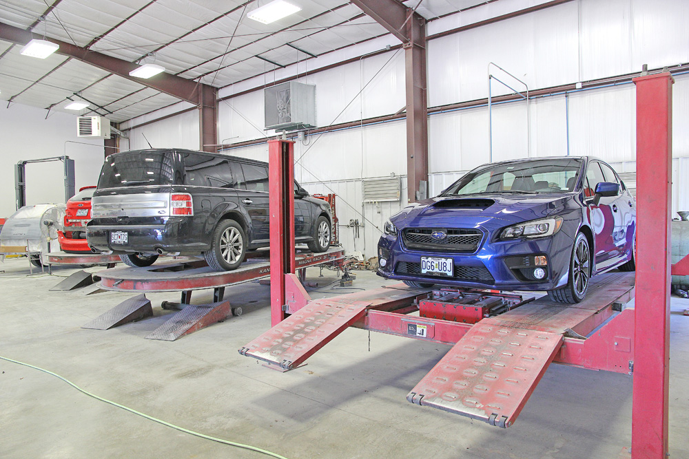 Vehicles on frame racks inside the 5th & Oak Autobody shop
